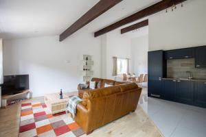 a living room with a brown leather couch and a tv at Cheltenham Cottage in Cirencester