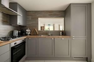 a kitchen with gray cabinets and a sink at Aintree Cottage in Cirencester +16 photos