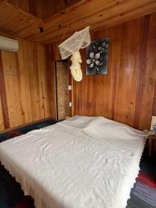 a bedroom with a white bed in a wooden wall at Peaceful Waterfall Homestay - Nhà Bên Thác in Hoat