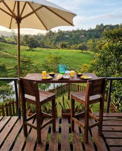 a wooden table with two chairs and an umbrella at Encanto Glamping in Las Dalias