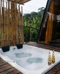 a hot tub on a deck with two bottles of beer at Encanto Glamping in Las Dalias