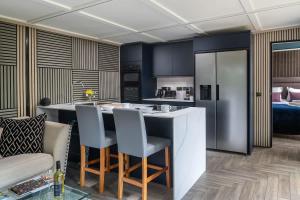 a kitchen with blue cabinets and a kitchen island with chairs at Badgers Sett in Hankerton