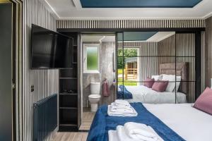 a bedroom with two beds and a tv and a bathroom at Badgers Sett in Hankerton