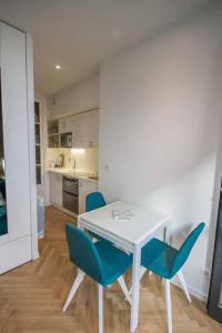 a white table with blue chairs in a kitchen at Studio Royan in Royan