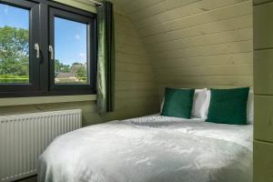 a bed sitting in a room with two windows at Squirrels Drey in Hankerton