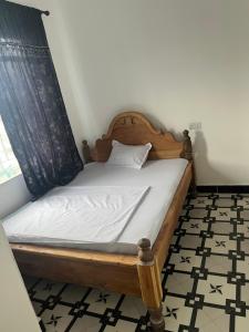 a bed with a wooden frame in a room at Amour Coco Stay in Chaki Chaki