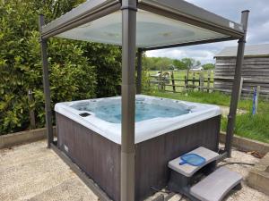 a jacuzzi tub with an umbrella in a yard at The Roundhouse Yurt in Colchester