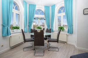 a dining room with blue curtains and a table and chairs at Ferienwohnung 10 Haus Metropol in Binz