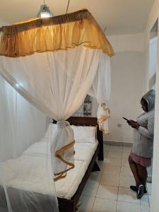 a woman standing next to a bed with a canopy at Jad Captains Hotel in Machakos