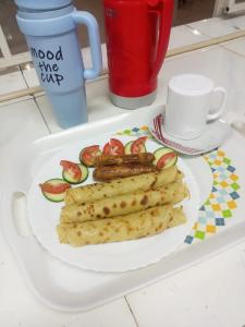 a plate of food with sausages and tomatoes on a table at Jad Captains Hotel in Machakos
