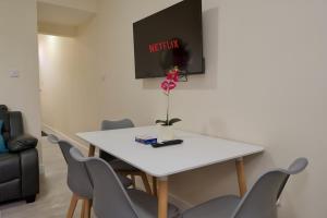 a white table with chairs and a vase with a flower on it at Hamilton's Rest Serviced Accommodation - Coventry in Coventry