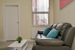 a living room with a brown leather couch with blue pillows at Hamilton's Rest Serviced Accommodation - Coventry in Coventry