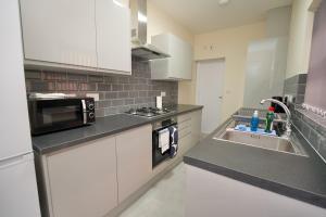 a kitchen with a sink and a microwave at Hamilton's Rest Serviced Accommodation - Coventry in Coventry +33 photos