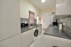a kitchen with a washer and a washing machine at Hamilton's Rest Serviced Accommodation - Coventry in Coventry
