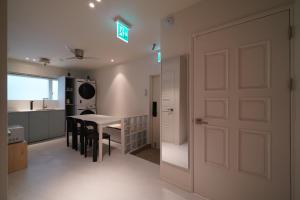 a white kitchen with a table and chairs and a door at Covon Stay in Busan +57 photos