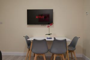 a table with four chairs and a tv on a wall at Hamilton's Rest Serviced Accommodation - Coventry in Coventry