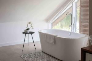 a white bath tub in a bathroom with a window at Malachite in South Cerney