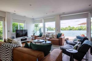 a living room with couches and a television and water at Malachite in South Cerney