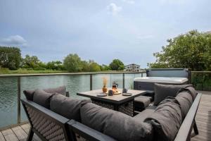 eine Terrasse mit Sofa und Tisch direkt am Wasser in der Unterkunft Maricor in South Cerney