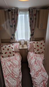 two beds in a small room with a window at The Speculation Inn - 3 Bedroom Static Caravan in Pembroke
