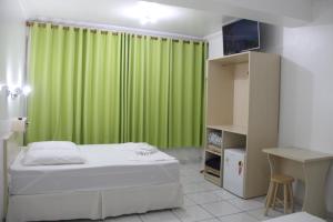 a bedroom with a bed and a green curtain at Oasis Chartouni Hotel in Blumenau +30 photos