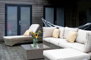 a patio with white couches and a table with flowers at Goose Landing in South Cerney