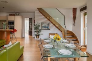 a dining room with a glass table and a staircase at Goose Landing in South Cerney