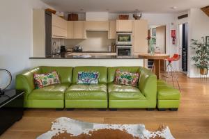 a green couch in a living room with a kitchen at Goose Landing in South Cerney