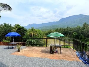 a patio with two tables and an umbrella at Nariman's riverstone hevan Resort in Kelakam
