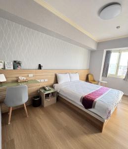 a bedroom with a bed and a desk and a chair at Green Yard Business Hotel in Miaoli