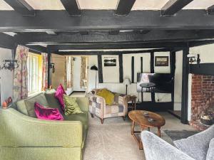 a living room with two couches and a piano at Willow Cottage in Framlingham