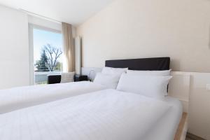 a white bed in a room with a window at first Apart in Erlangen