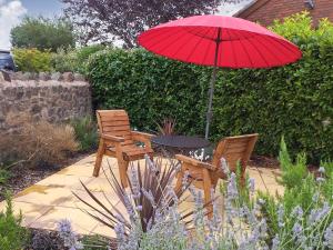 a table and two chairs with a red umbrella at Little Acorns in Great Malvern