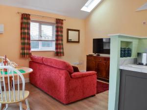 a living room with a red couch and a tv at The Squirrels in Great Malvern