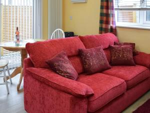 a red couch with pillows in a living room at The Squirrels in Great Malvern