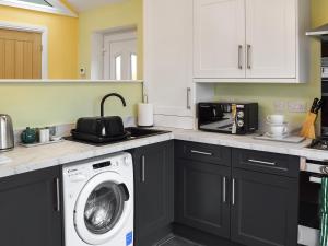 a kitchen with a washer and dryer in it at The Squirrels in Great Malvern