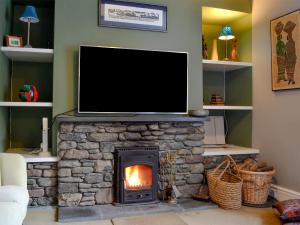 a living room with a stone fireplace with a flat screen tv at Trevene in Buttermere