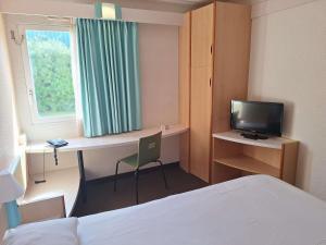 a room with a bed and a desk with a television at Hotel ibis Setubal in Setúbal +48 photos