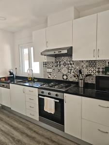 a kitchen with white cabinets and a stove top oven at Marca 34 in Monção