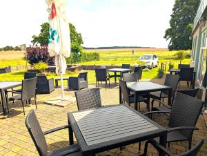 a patio with tables and chairs and an umbrella at Pension Müritzblick in Gotthun