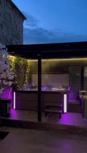 a patio with a bench under avisor with purple lights at Luxehaus MCR in Manchester