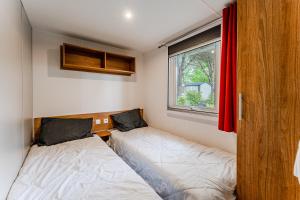 a small bedroom with two beds and a window at Mobil-home Badji in Gastes +17 photos