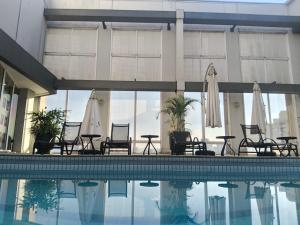 a pool with chairs and umbrellas in a building at Airport Gru Flats in Guarulhos