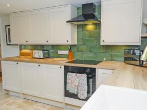 a kitchen with white cabinets and a black oven at Carters Cottage - Ukc3947 in Puncknowle
