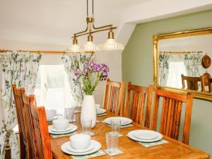 a dining room table with a vase of flowers on it at Carters Cottage - Ukc3947 in Puncknowle