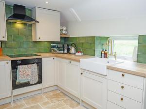 a kitchen with white cabinets and a sink at Carters Cottage - Ukc3947 in Puncknowle