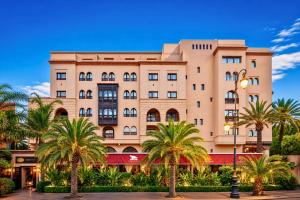 a building with palm trees in front of it at Hivernage Marrakech in Marrakesh