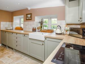 a kitchen with white cabinets and a sink at Thatcher's Cottage - Ukc3956 in Puncknowle