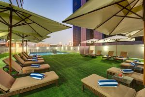 une terrasse avec des chaises longues et des parasols dans l'établissement Royal Continental Hotel, à Dubaï