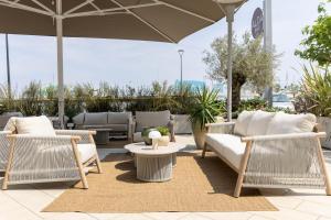 a patio with chairs and tables and an umbrella at Alda Seaview Hotel in Cervia